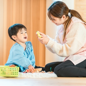 保育士とおもちゃで遊ぶ子ども
