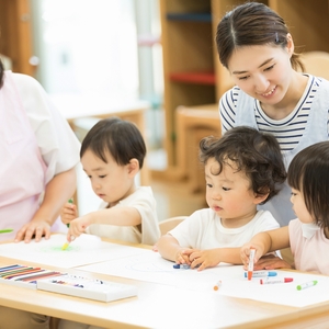 保育者に見守られながらお絵かきをする園児