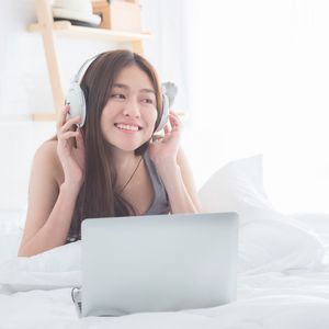 ベッドで音楽を聴く女性
