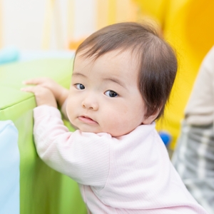 つかまり立ちをする0歳児 