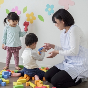 おもちゃで遊ぶ保育士と1歳児

